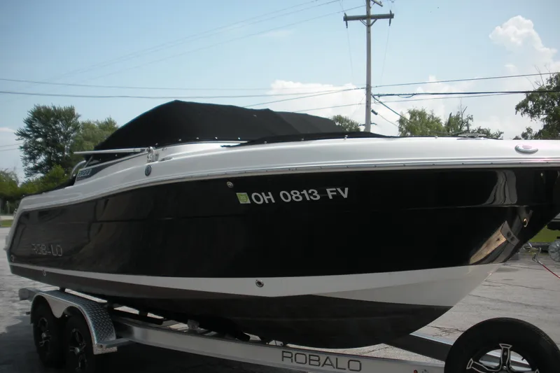 Slide: The Image of 2017 Robalo R227DC boat on trailer, black hull, parked outdoors. - 2