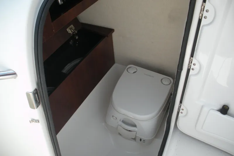 Slide: The Image of 2017 Robalo R227DC boat interior with compact marine toilet and storage. - 5
