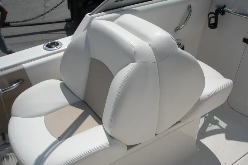 Slide: The Image of White cushioned seat on 2017 Robalo R227DC boat, featuring sleek design and cup holder. - 9