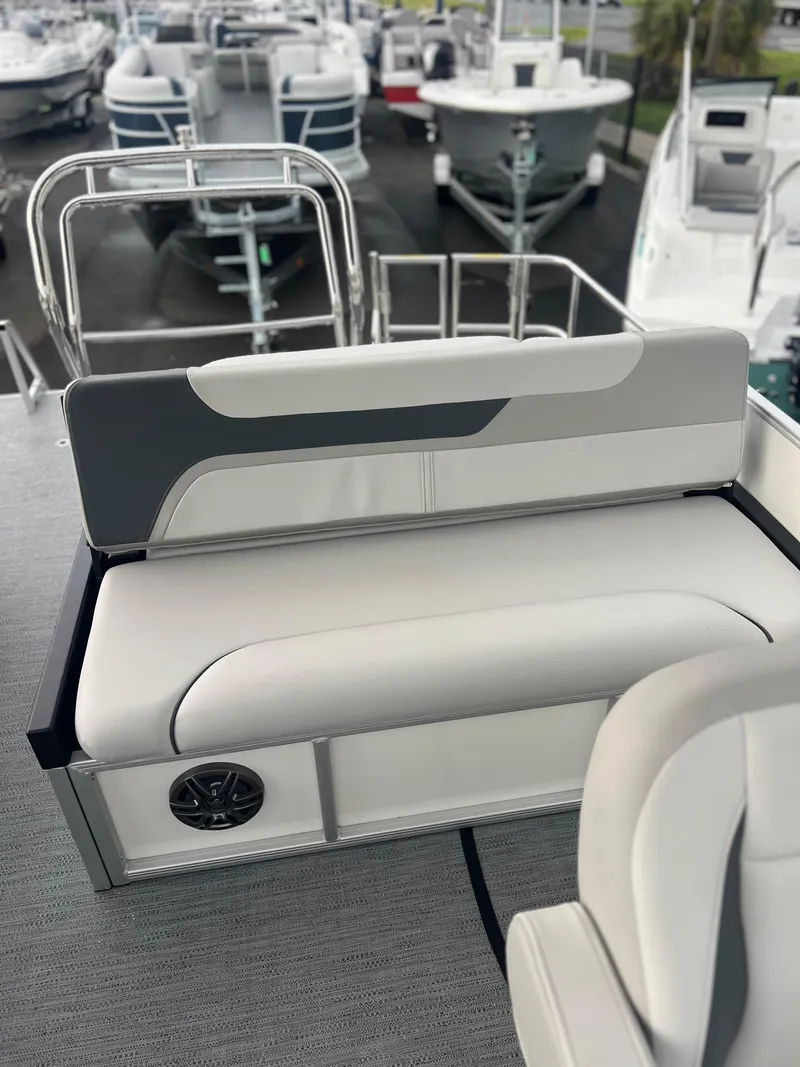 Slide: The Image of 2026 Sweetwater 2286SFLC boat interior with cushioned seating and speaker, docked among other boats. - 7