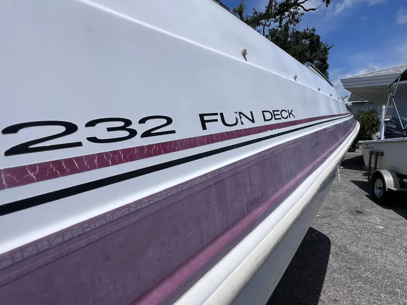 Slide: The Image of 2000 Hurricane FunDeck GS 232 OB boat with purple stripe, parked on a sunny day. - 9
