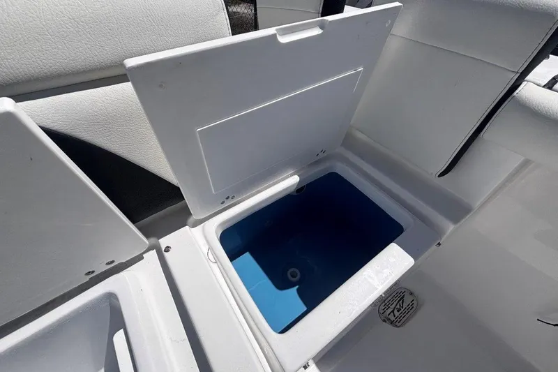 Slide: The Image of Open storage compartment on 2026 Tidewater 272 LXF boat, featuring white and blue interior. - 21