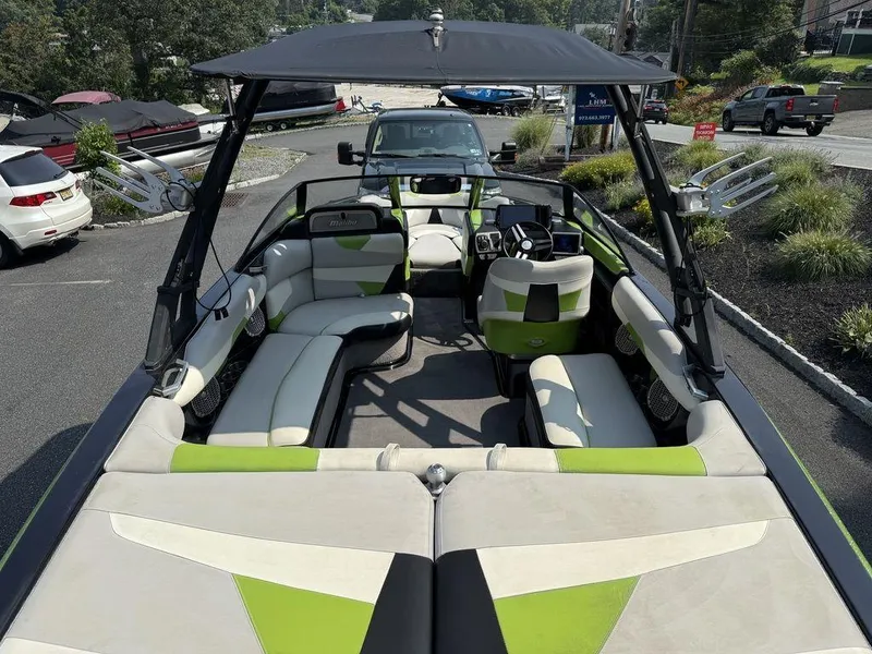 Slide: The Image of 2015 Malibu 22 VLX boat with green and white interior, parked outdoors. - 12