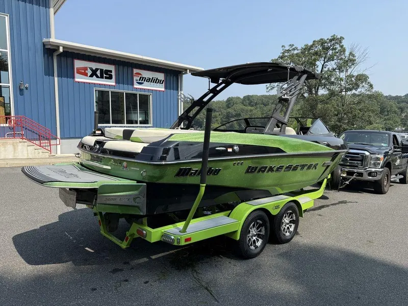 Slide: The Image of 2015 Malibu 22 VLX Wakesetter boat in vibrant green on trailer, parked outside dealership. - 4
