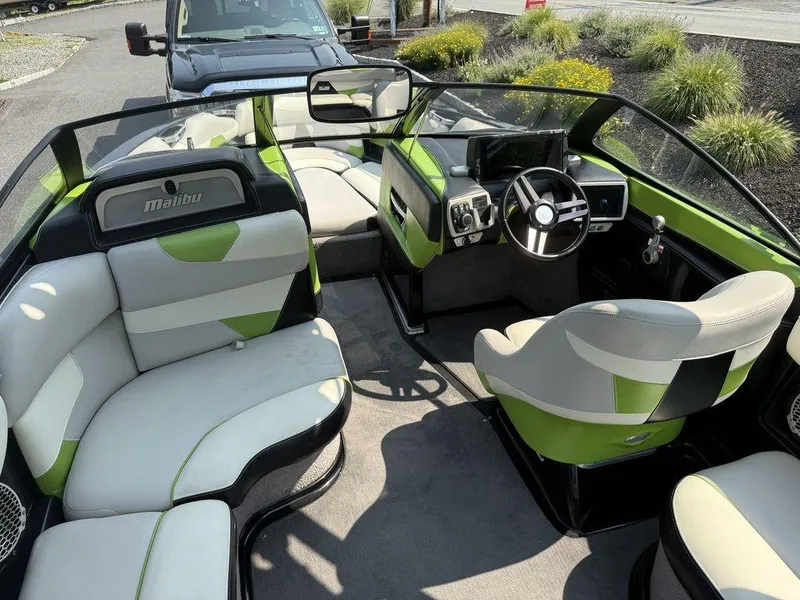 Slide: The Image of 2015 Malibu 22 VLX boat interior with green and white seating, steering wheel, and dashboard. - 8