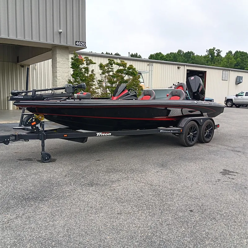 Slide: The Image of 2025 Triton 20XP boat on trailer, parked outside industrial building. - 2