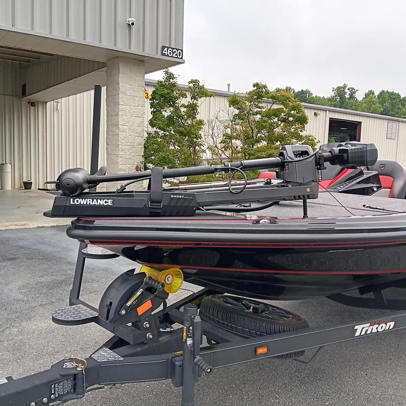 Slide: The Image of 2025 Triton 20XP boat with Lowrance Ghost trolling motor, parked outside a building. - 8