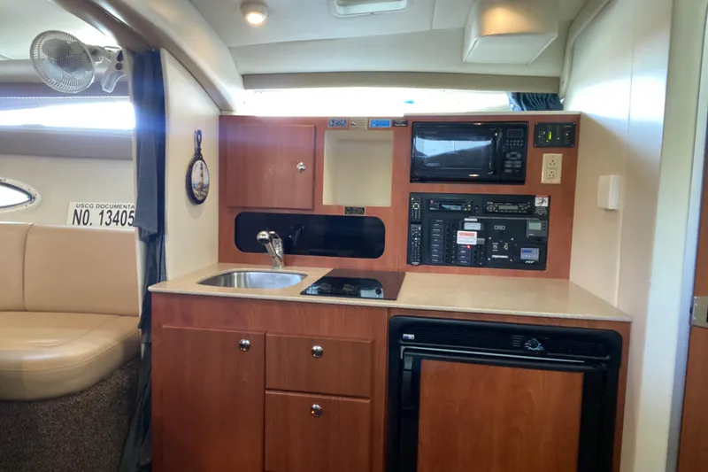 Slide: The Image of 2005 Bayliner 325 yacht interior with kitchenette, featuring sink, stove, and microwave. - 23