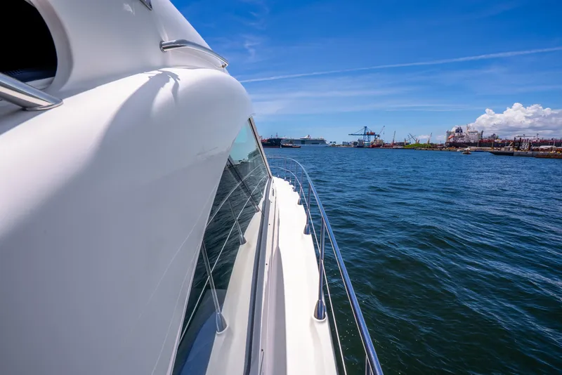 Slide: The Image of 2008 Sea Ray 60 Sundancer yacht cruising near a busy harbor under a clear blue sky. - 43
