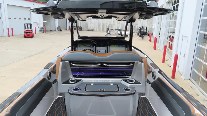 Slide: The Image of 2023 Sunsation 32 CCX boat interior with modern dashboard and seating at a marina. - 11