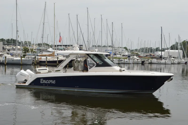 Slide: The Image of 2023 Tiara Yachts 34 LS boat docked in marina, surrounded by sailboats. - 4
