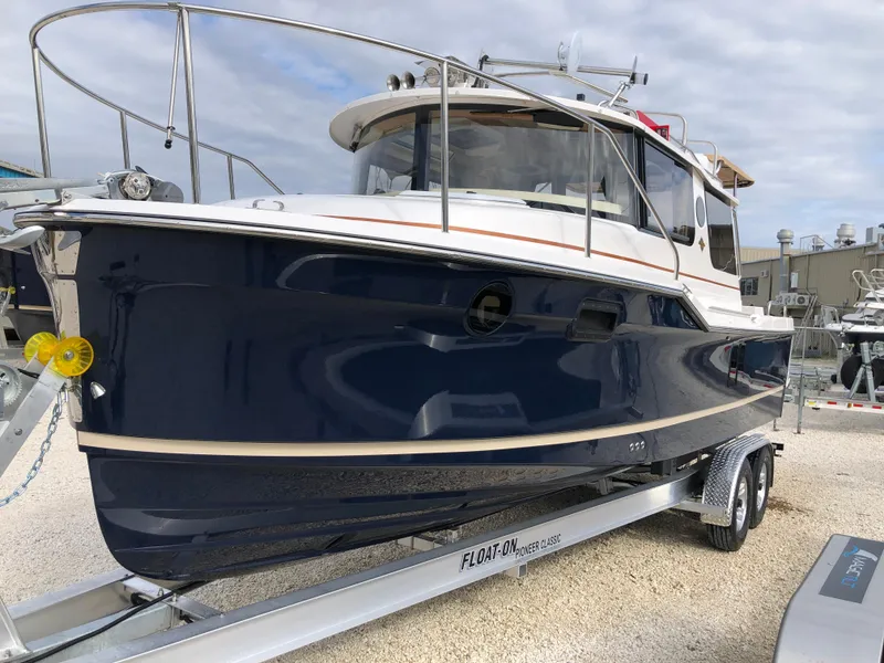 The Image of 2026 Ranger Tugs R-27 boat on trailer, blue hull, docked outdoors. - 0
