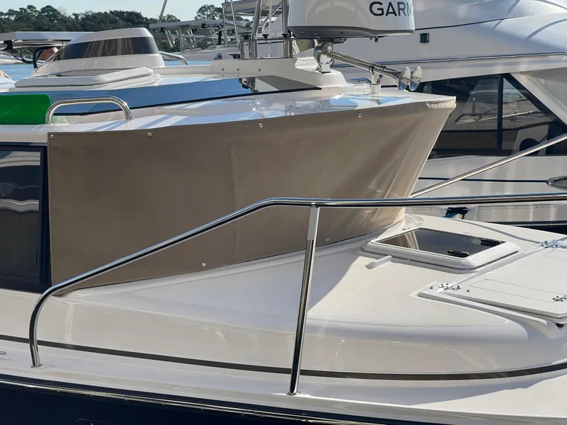 Slide: The Image of 2026 Ranger Tugs R-27 boat deck with railing and hatch, featuring Garmin equipment. - 2