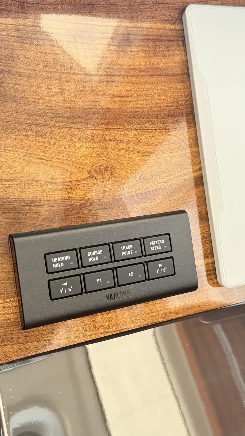 Slide: The Image of Yamaha control panel on 2026 Ranger Tugs R-27, featuring navigation buttons on wood surface. - 24