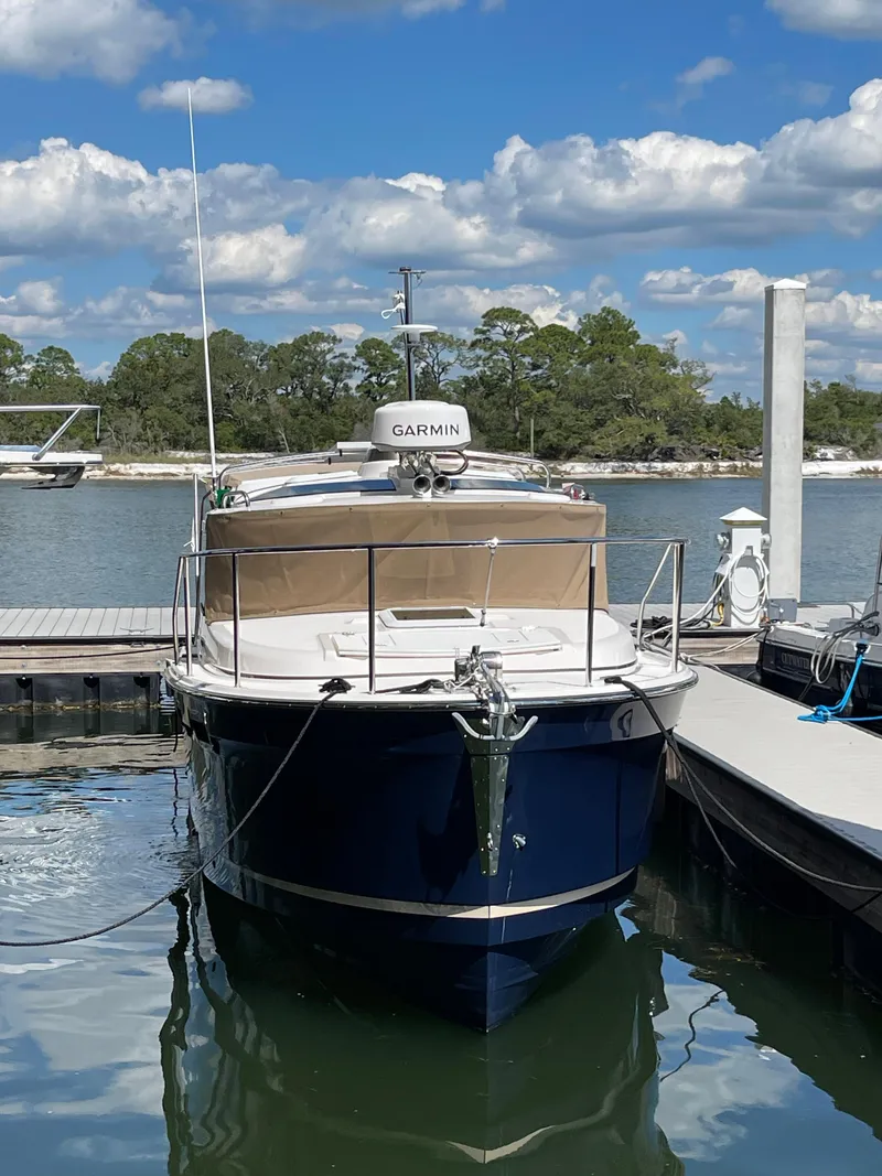 Slide: The Image of 2026 Ranger Tugs R-27 boat docked, featuring Garmin equipment, under a partly cloudy sky. - 3