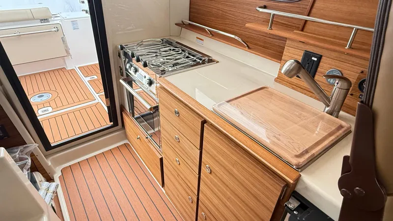Slide: The Image of Interior of 2026 Ranger Tugs R-27 boat featuring a compact kitchen with stove and sink. - 38