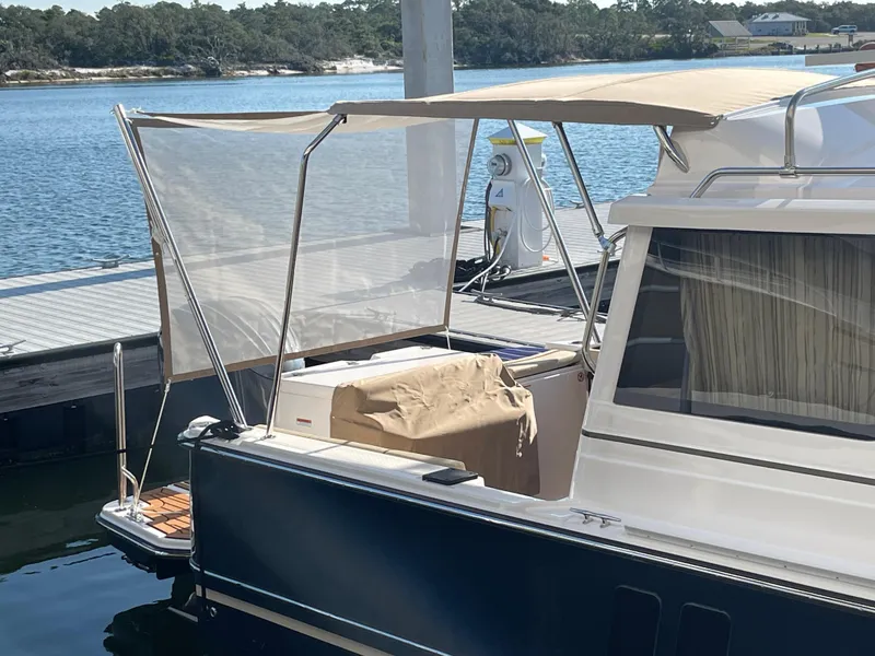 Slide: The Image of 2026 Ranger Tugs R-27 docked, featuring a covered deck and scenic waterfront view. - 4