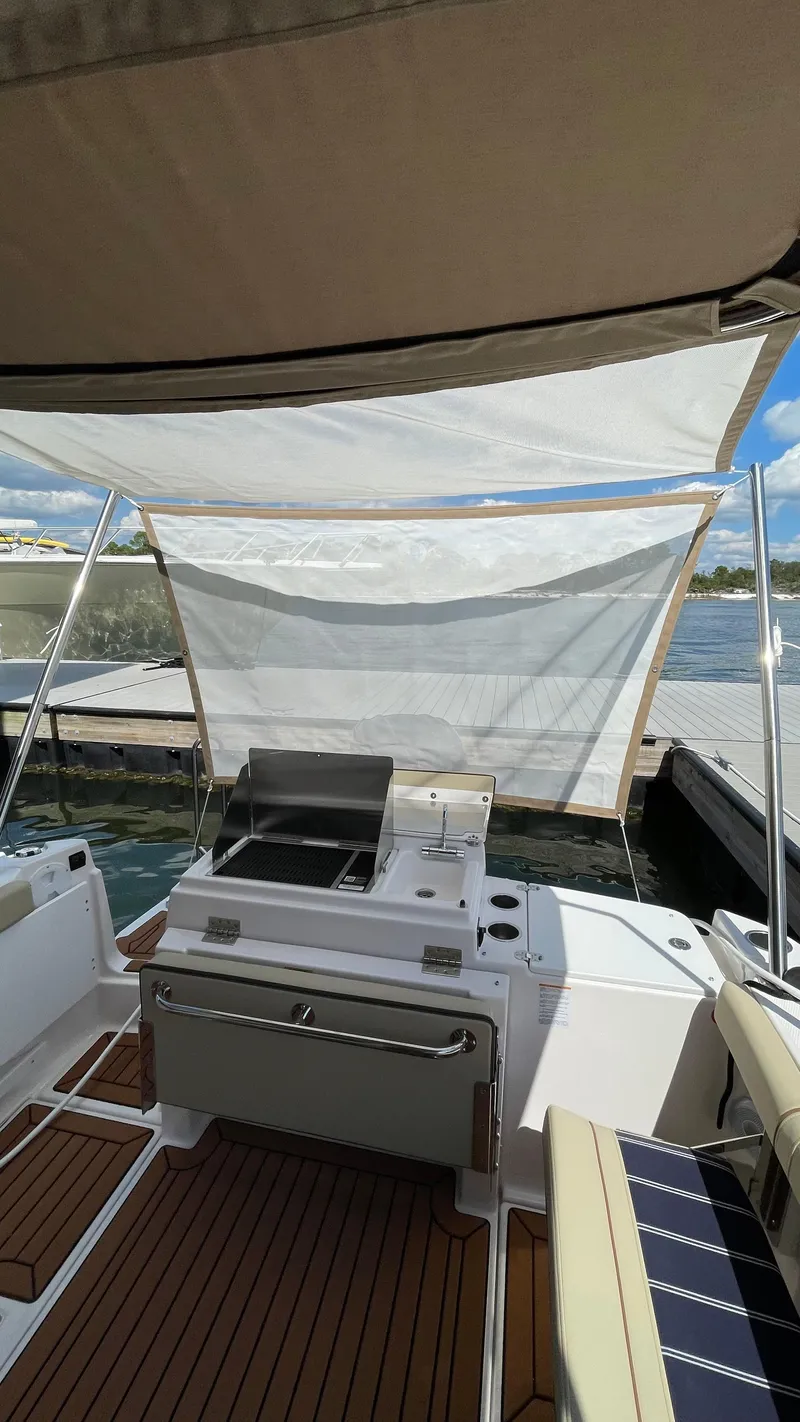 Slide: The Image of 2026 Ranger Tugs R-27 boat with outdoor grill and seating, docked by the water. - 5