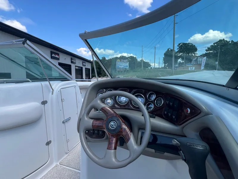 Slide: The Image of 2006 Crownline 270 BR boat dashboard with steering wheel and gauges under a clear blue sky. - 11