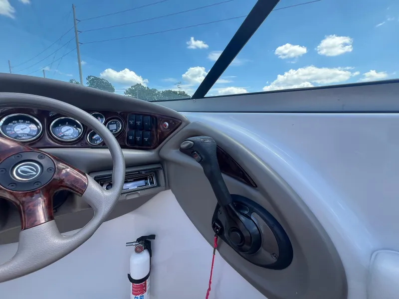 Slide: The Image of 2006 Crownline 270 BR boat dashboard with steering wheel and controls under a blue sky. - 17