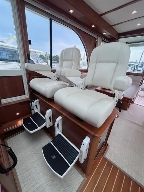 Slide: The Image of Interior of 2021 Sabre 45 Salon Express with luxurious white captain chairs and footrests. - 27