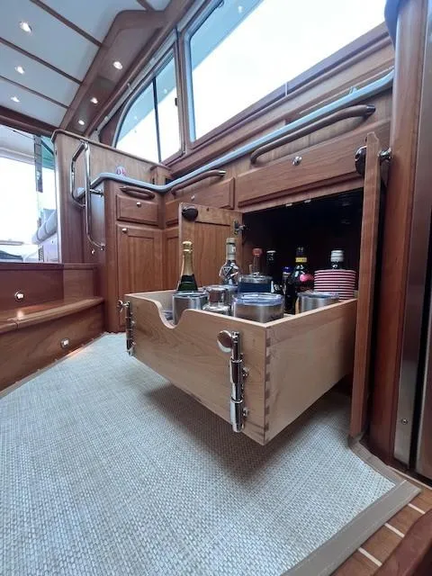 Slide: The Image of 2021 Sabre 45 Salon Express interior with open drawer displaying beverages and glasses. - 44