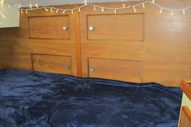 Slide: The Image of Cozy cabin interior of 1978 Moody 33 MkI sailboat with wooden paneling and string lights. - 7