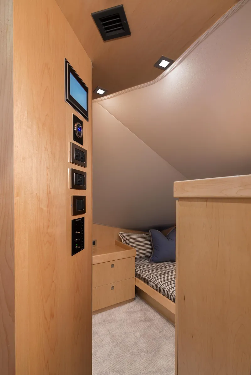 Slide: The Image of Interior of 2027 Viking 82 Skybridge yacht with modern wood paneling and cozy sleeping area. - 20