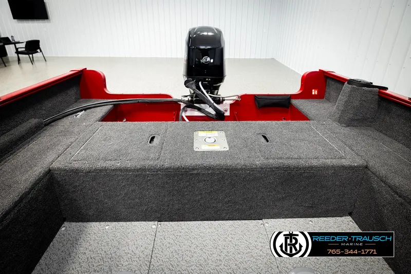 Slide: The Image of 2026 Lund 1650 Rebel XL SS boat interior with motor, gray carpet, and red accents. - 21