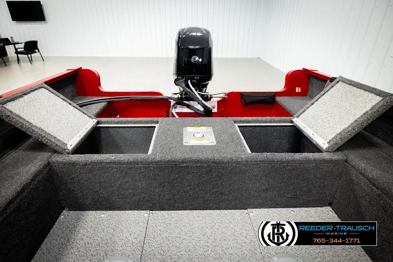 Slide: The Image of 2026 Lund 1650 Rebel XL SS boat interior with storage compartments and motor, displayed indoors. - 22
