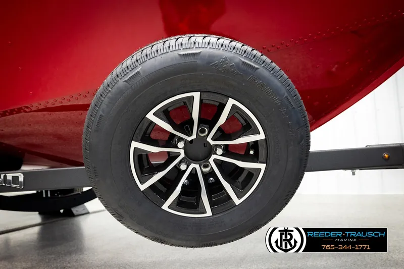 Slide: The Image of 2026 Lund 1650 Rebel XL SS boat trailer wheel, black and silver rim, Reeder-Trausch Marine logo. - 44