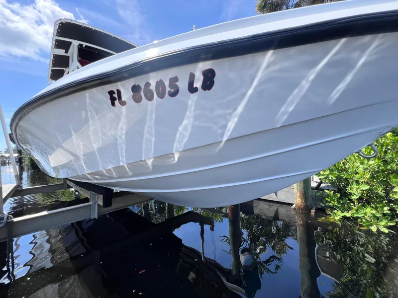 Slide: The Image of White Concept 23 boat from 2000 on a lift, reflecting on water. - 12