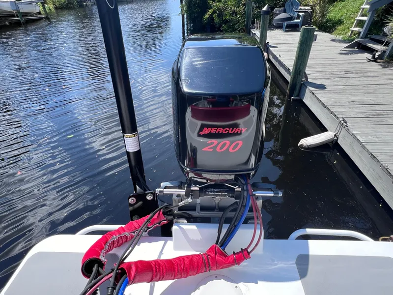 Slide: The Image of Outboard motor on a boat docked by a wooden pier, featuring a Mercury 200 engine. - 14