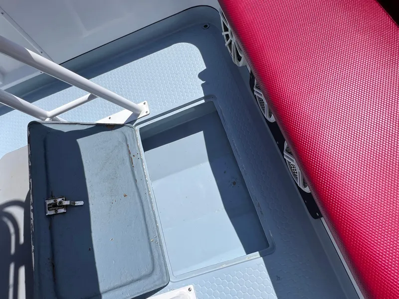 Slide: The Image of Open storage compartment on a Concept 23 boat, featuring red seating and textured flooring. - 17