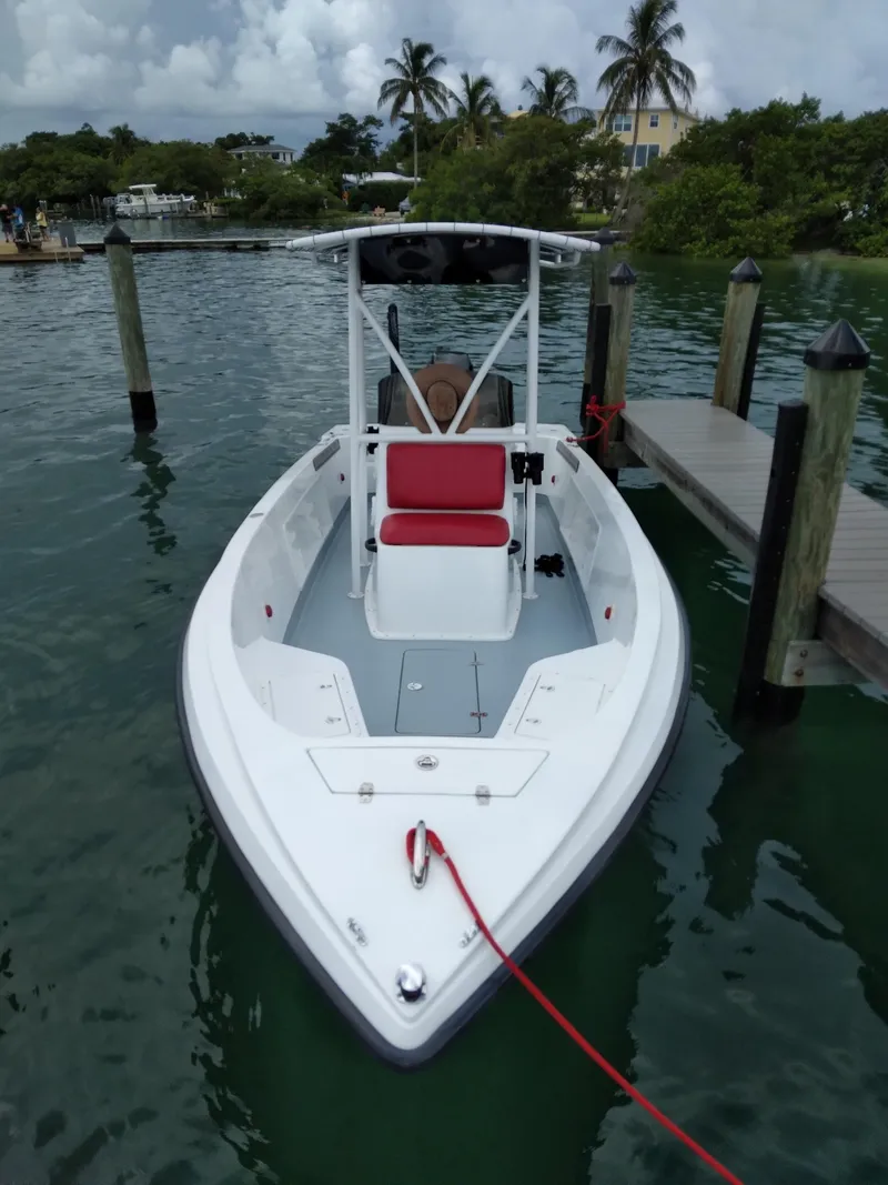 Slide: The Image of White Concept 23 boat docked, featuring red seating, surrounded by calm water and palm trees. - 5