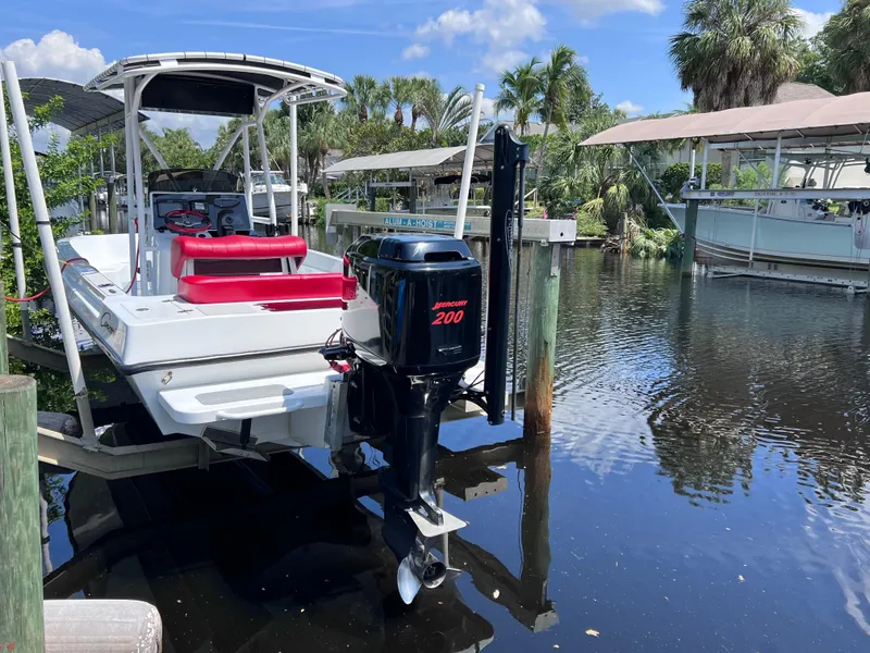 Slide: The Image of Boat docked with Mercury 200 engine, Concept 23 model, surrounded by palm trees and calm water. - 9