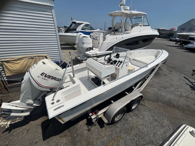 Slide: The Image of 1996 Superboat 24 on trailer with Evinrude outboard motor, parked near other boats. - 6