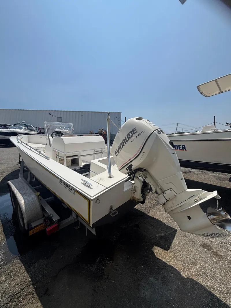 Slide: The Image of 1996 Superboat 24 with Evinrude engine on trailer, parked outdoors under clear sky. - 8