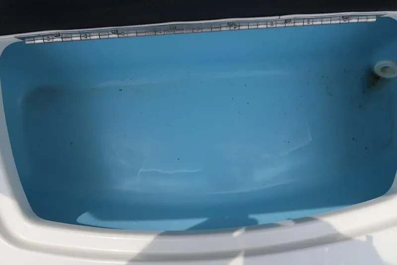 Slide: The Image of Open storage compartment in 2021 Chaparral 23 SSi boat, featuring a clean blue interior. - 15