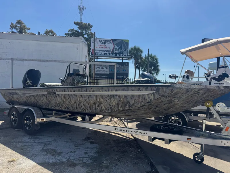The Image of 2025 Ranger RB210 boat on trailer, camo design, parked outdoors. - 0