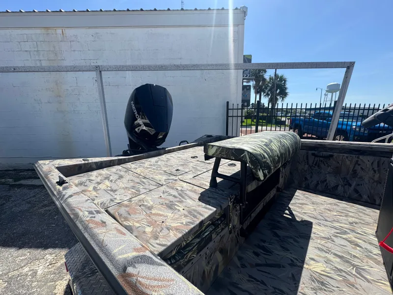 Slide: The Image of 2025 Ranger RB210 boat with camouflage interior and Mercury outboard motor, parked outdoors. - 2