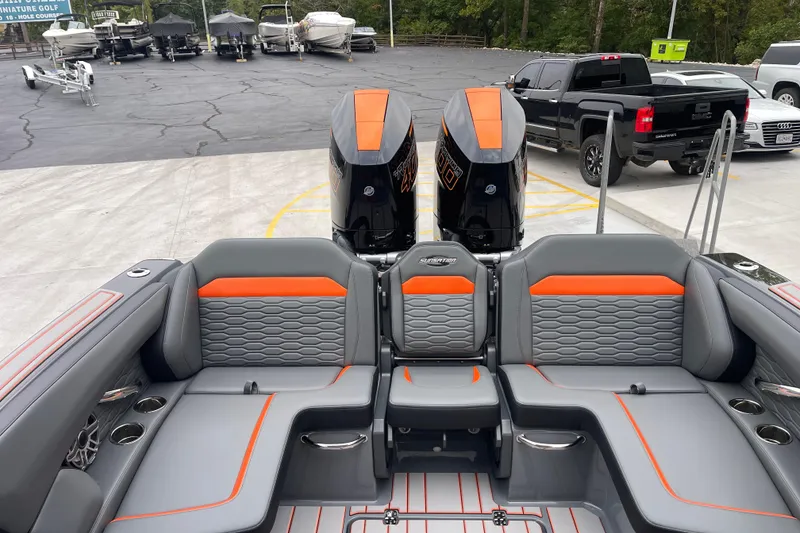 Slide: The Image of 2025 Sunsation 32 CCX boat interior with gray and orange seating, dual engines, and parked vehicles. - 13