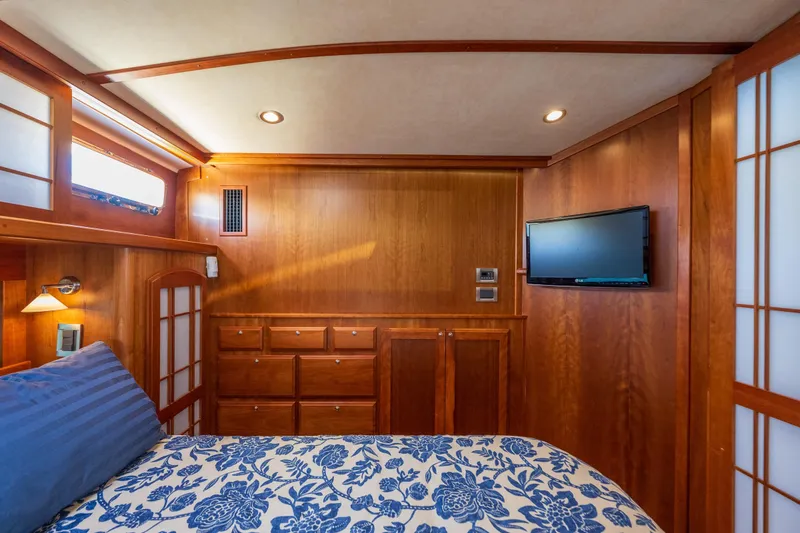 Slide: The Image of Luxurious wood-paneled bedroom in 2014 Sabre 48 Salon Express yacht with TV and floral bedding. - 31