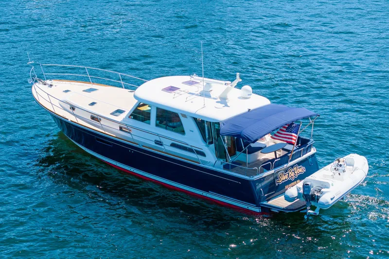 Slide: The Image of 2014 Sabre 48 Salon Express yacht cruising on blue water, featuring a sleek design and American flag. - 8