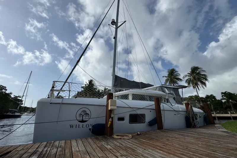 The Image of 2008 Lagoon 420 catamaran docked, surrounded by palm trees and a cloudy sky. - 0