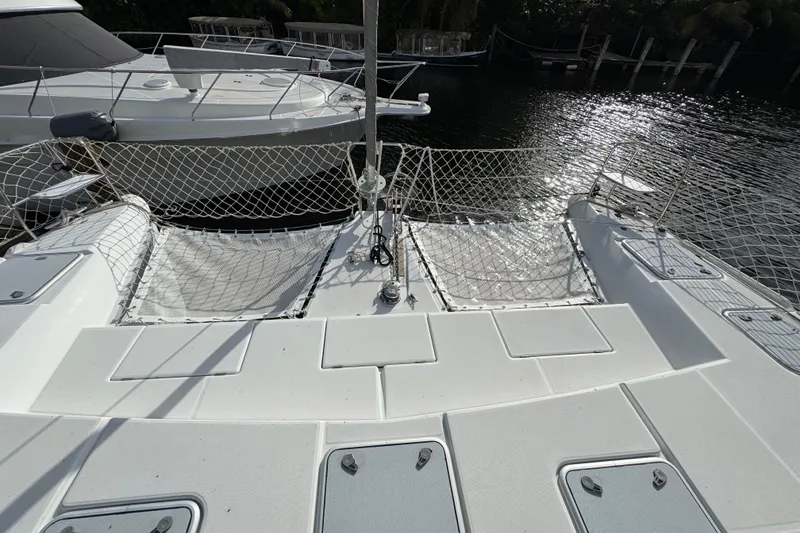 Slide: The Image of 2008 Lagoon 420 catamaran deck with netting, docked near other boats. - 2
