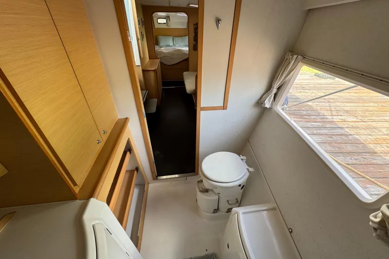 Slide: The Image of Interior of a 2008 Lagoon 420 yacht, featuring a compact bathroom and cozy bedroom. - 33