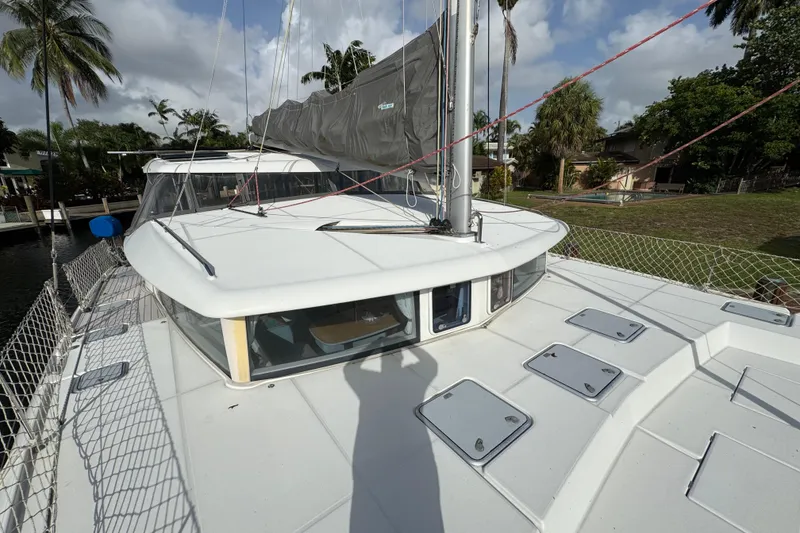 Slide: The Image of 2008 Lagoon 420 catamaran docked, featuring spacious deck and sail, surrounded by tropical scenery. - 8
