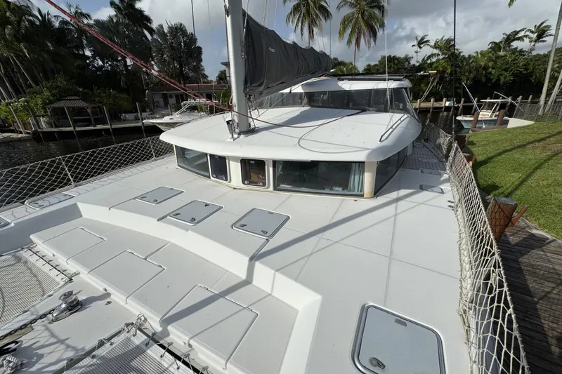 Slide: The Image of 2008 Lagoon 420 catamaran docked, featuring spacious deck and lush tropical surroundings. - 9