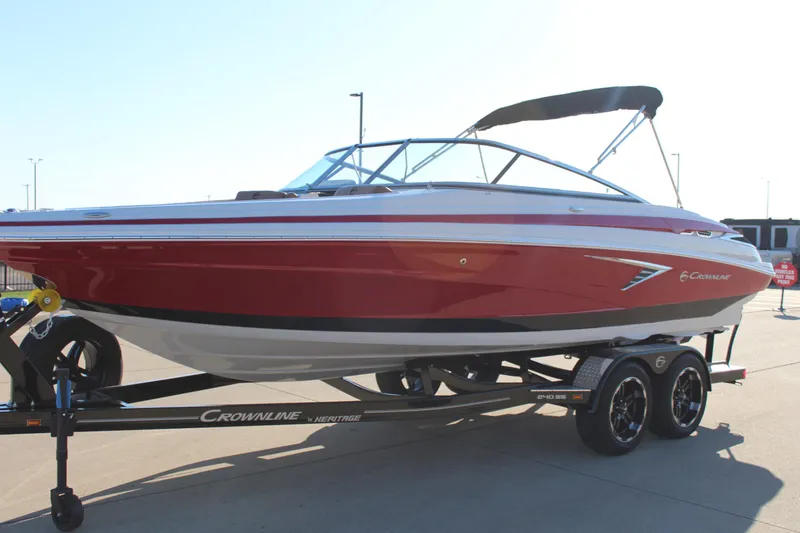 The Image of 2024 Crownline 240 SS boat on trailer, red and white design, parked outdoors. - 0